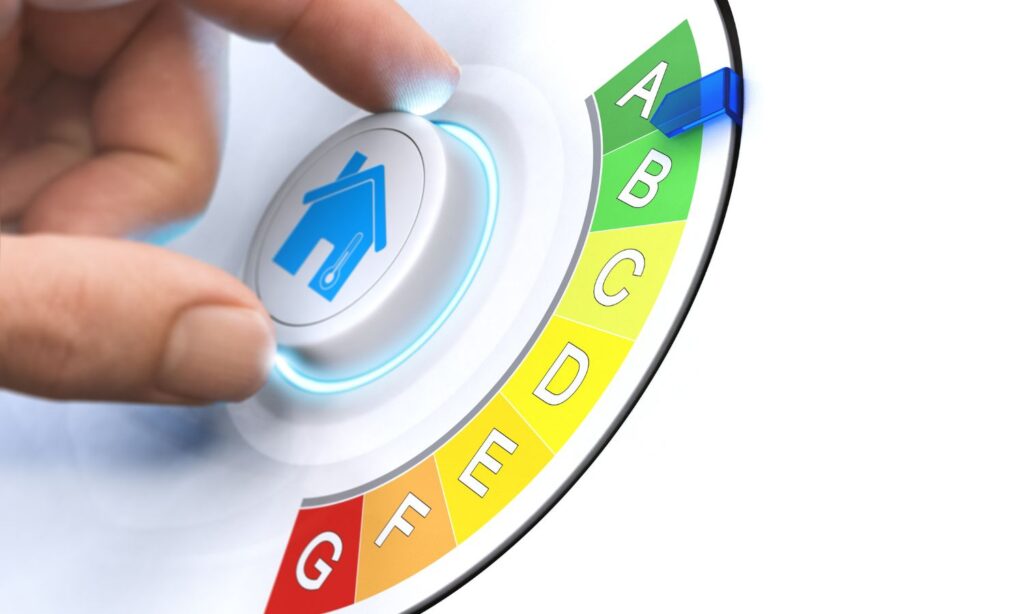 Hand turning a dial with a home icon, adjusting energy efficiency from red to green.