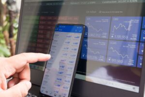 Close-up of a person's hands holding a modern smartphone with a clean, minimalist financial tracking or stock trading app ...